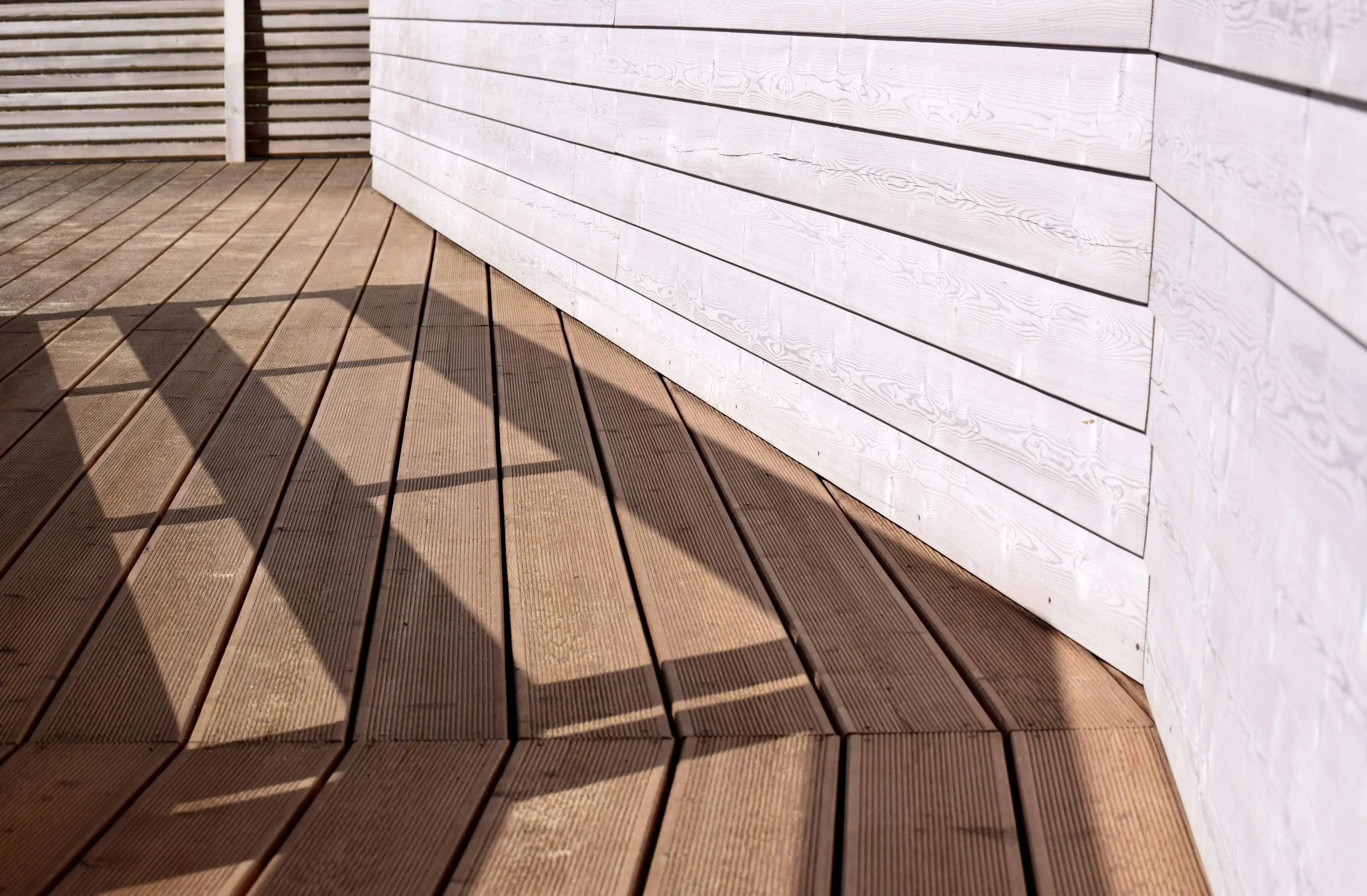 a wooden deck with a white wall behind it