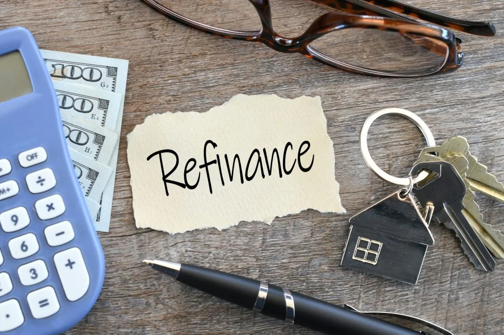 A piece of paper that says refinance next to keys, a pen, and a calculator