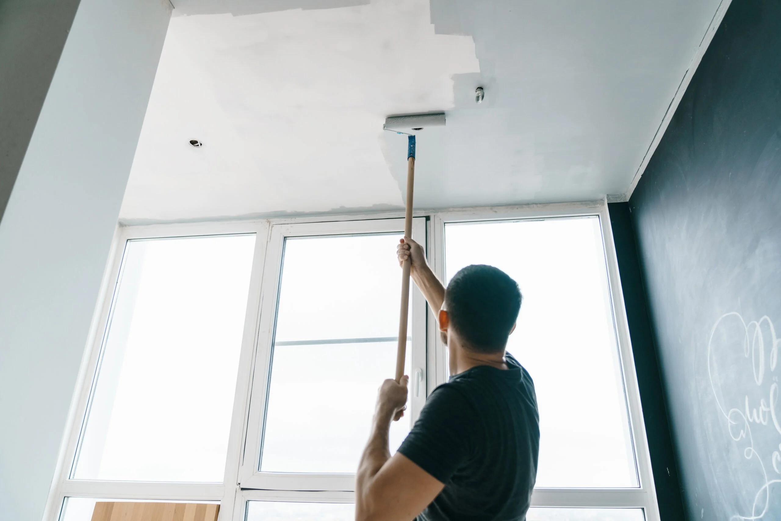 a man is painting the ceiling with a roller