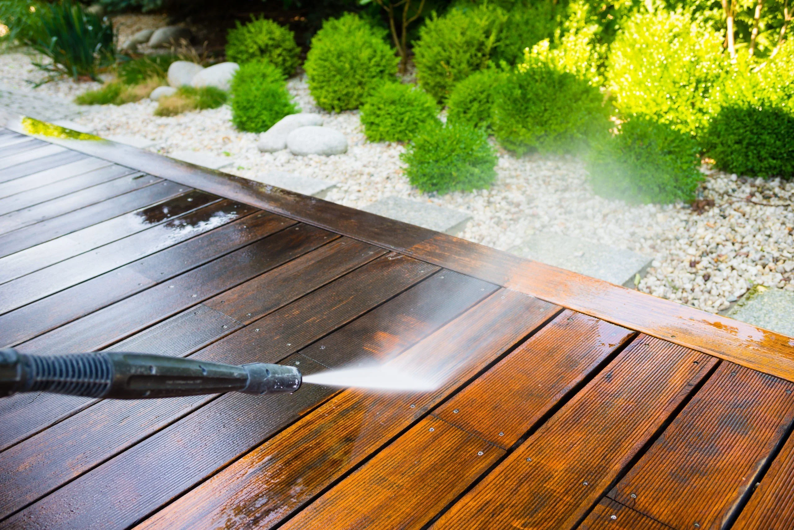 a person using a pressure washer on a wooden deck