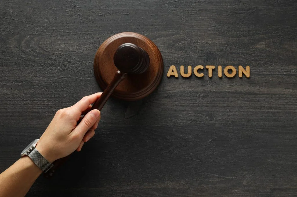 wooden-hammer-in-hand-and-word-auction-on-wooden-table