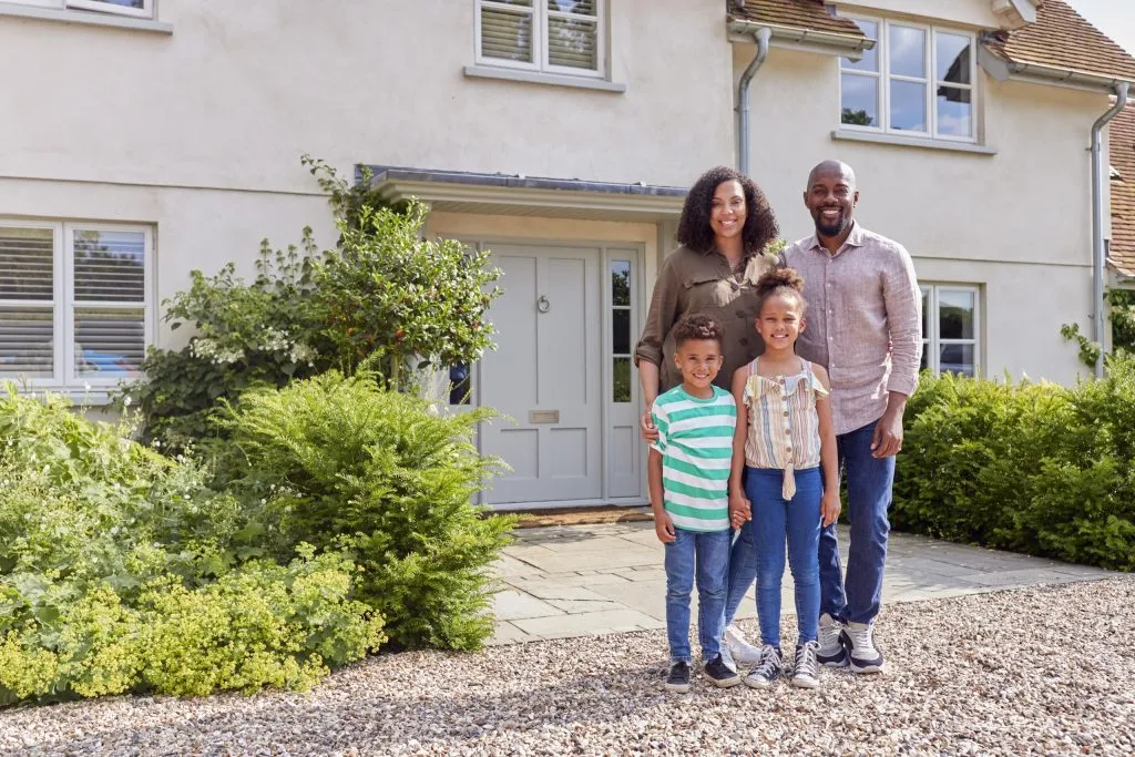 portrait-of-smiling-family-standing-outside-home