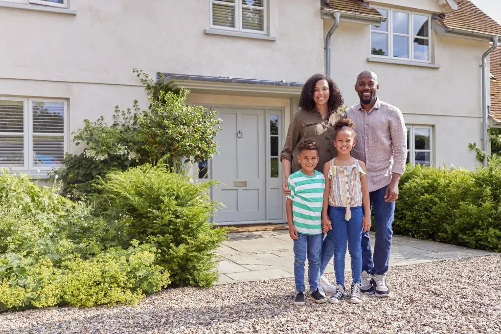 portrait-of-smiling-family-standing-outside-home